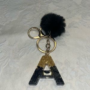 Bag charm or keychain with pom pom. Colors are black and gold